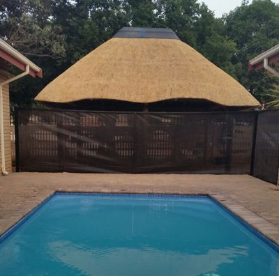 Thatched gazebo roof above a gate, beside a swimming pool